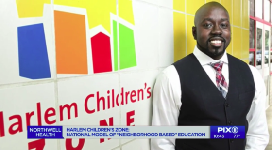 Kwame Owusu-Kesse standing in front of HCZ mural