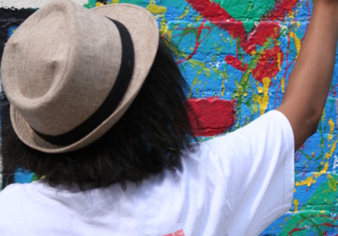 A woman paints a colorful mural on a wall.
