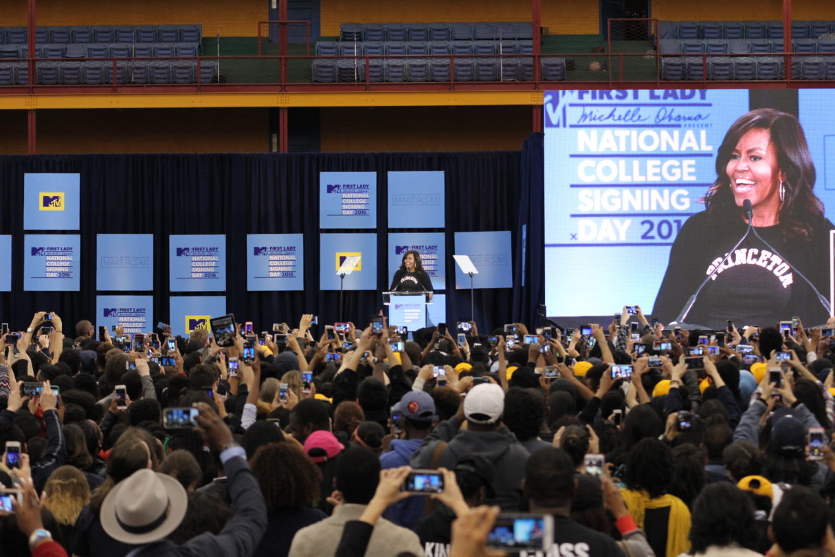 center for higher education and career support | Michelle Obama stands in front of a podium on a stage and speaks to hundreds of high school seniors on National College Signing Day