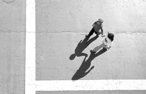 Black and white aerial image of two children walking on pavement
