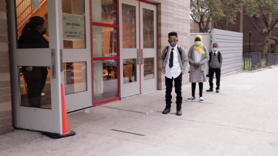 Students stand in front of school