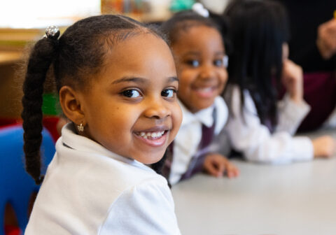 Two young female scholars smile at the camera