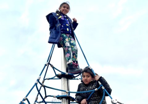 Two children climb on a playground.