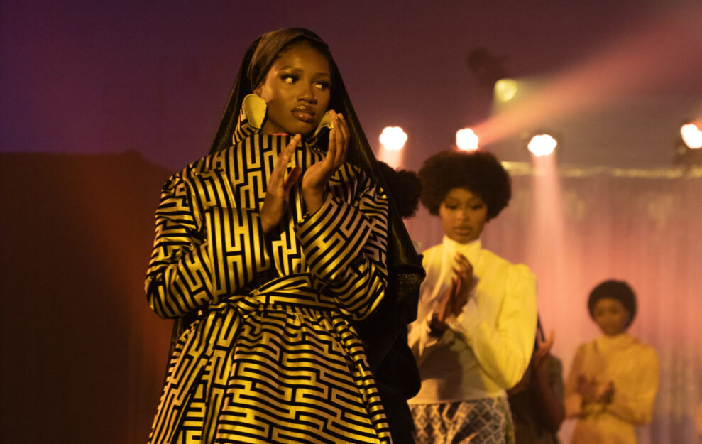 Zone high school programs fashion designer wears a gold dress and claps while walking the runway.