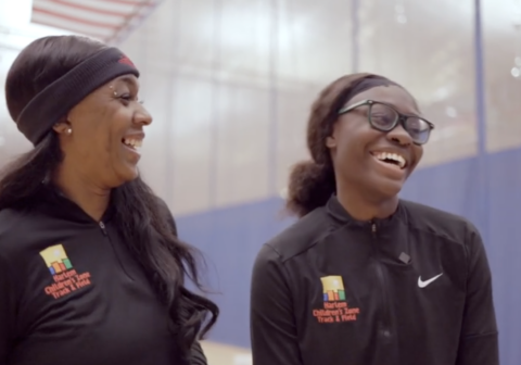 Two young women laughing in a gymnasium.