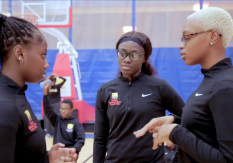 Three young woman conversing in a gymnasium.
