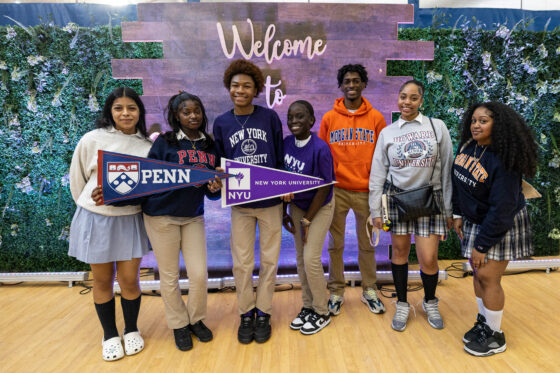 Harlem Children's Zone scholars wearing college attire and holding up college penants at National College Signing Day 2023