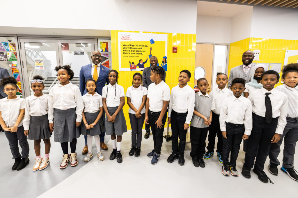 Kwame Owusu-Kesse, Geoffrey Canada, and Achil Petit stand with a group of students in the new building.