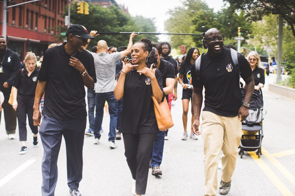 Geoffrey Canada, Anne Williams-Isom, and Kwame Owusu-Kesse walk down the street together.