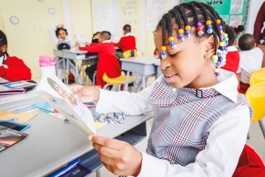 A student in a plaid uniform reads a book in class.