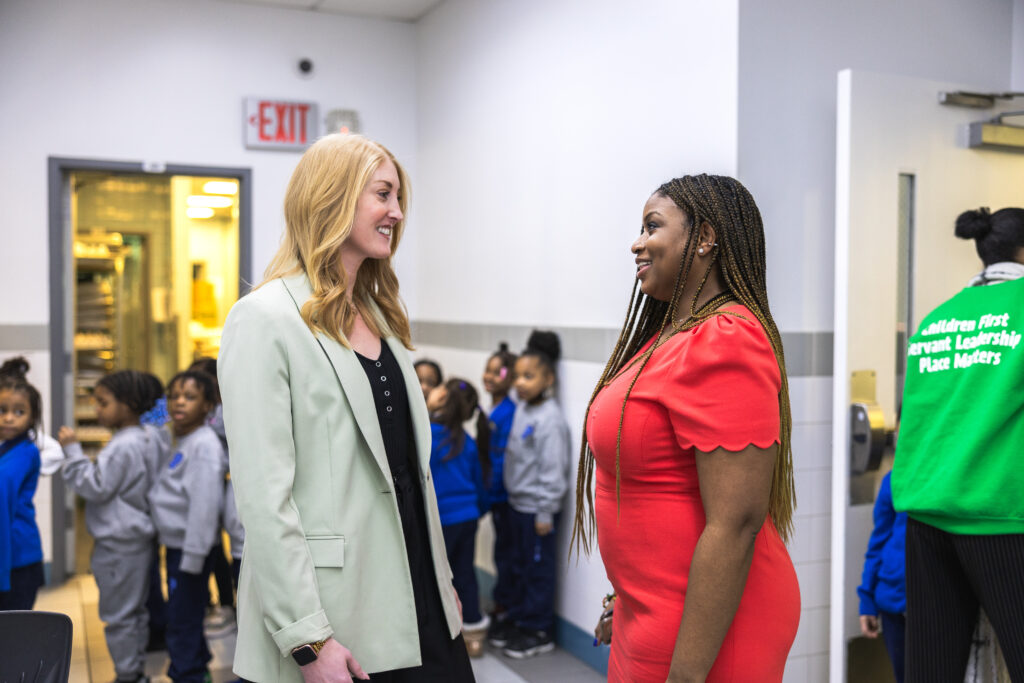 Deirdre Schwiring and Madelaine Schultz converse in a school hallway.