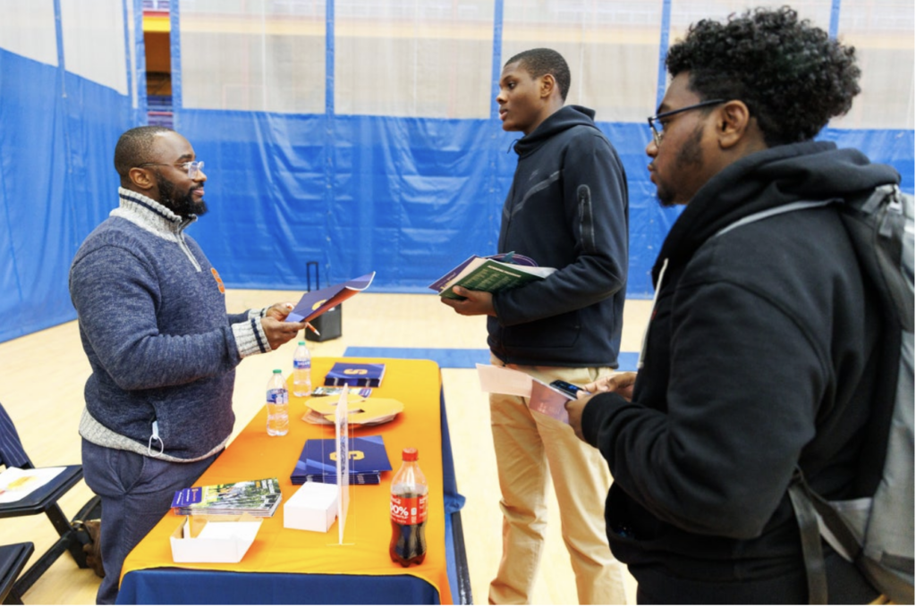 A Wealth Builds staff member speaks to two students at a table.