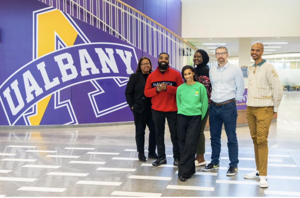Various College Success Office staff members pose in front of a staircase with the text "U-Albany" on it.