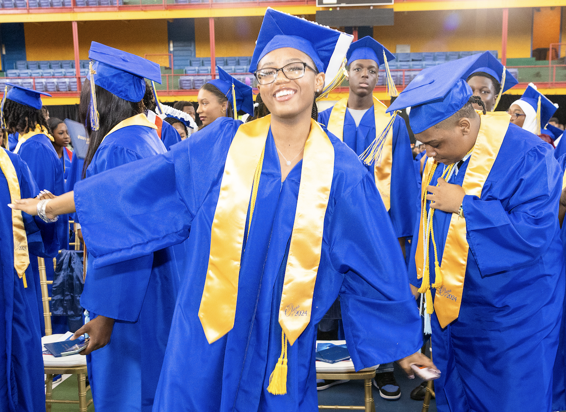 Teenage girl wearing blue graduation outfit and golden sash.