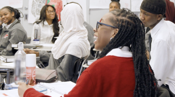 Shania Sanders laughs, facing away from the camera, in a classroom.