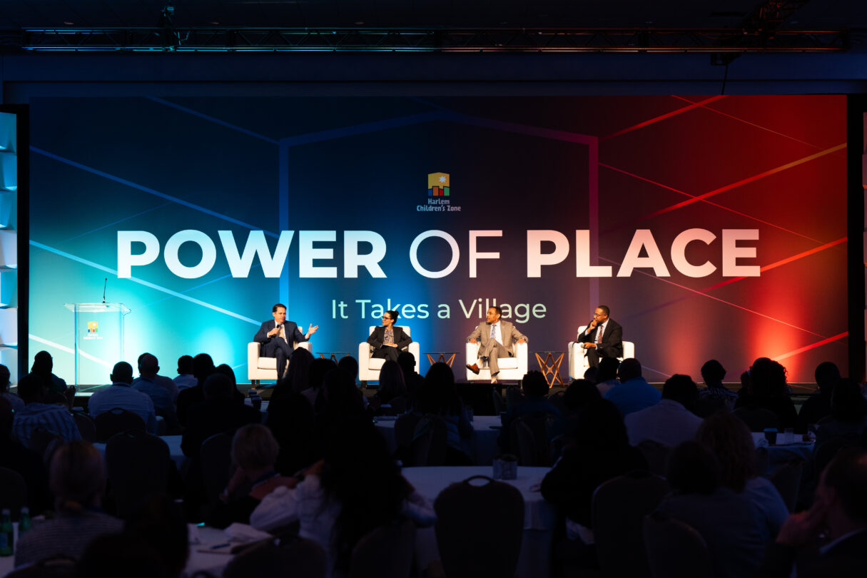 A panel of speakers sit on a stage