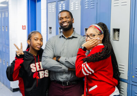 Three adults standing next to lockers.