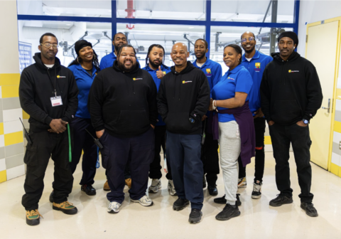 HCZ Facilities Team in uniforms standing in lobby of Promise Academy building.