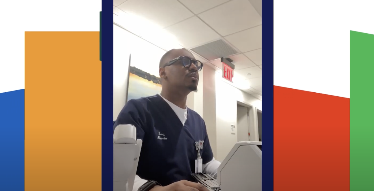 Person in medical scrubs sitting at a desk looking at a computer.