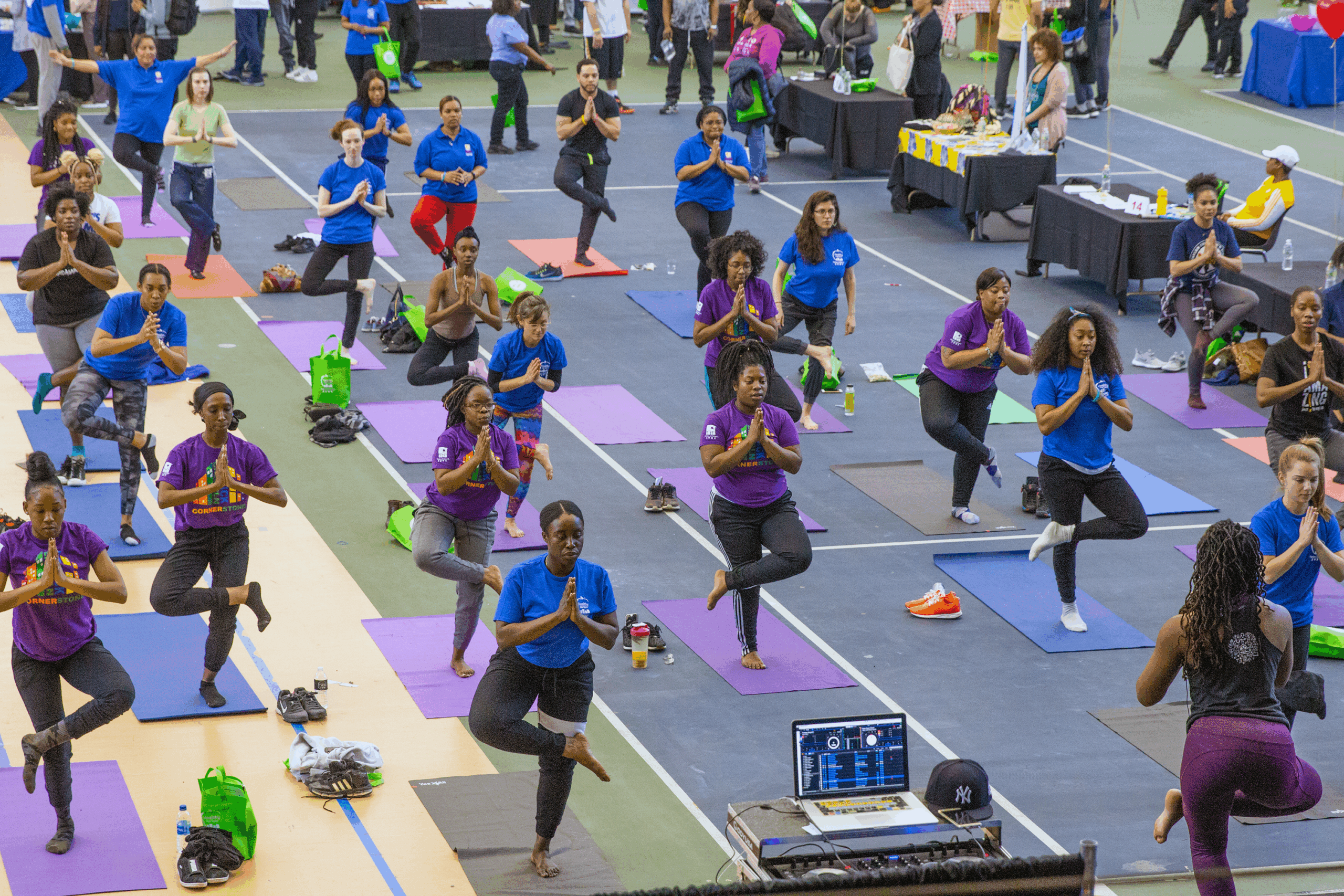 A class of men and women hold yoga poses in a gym