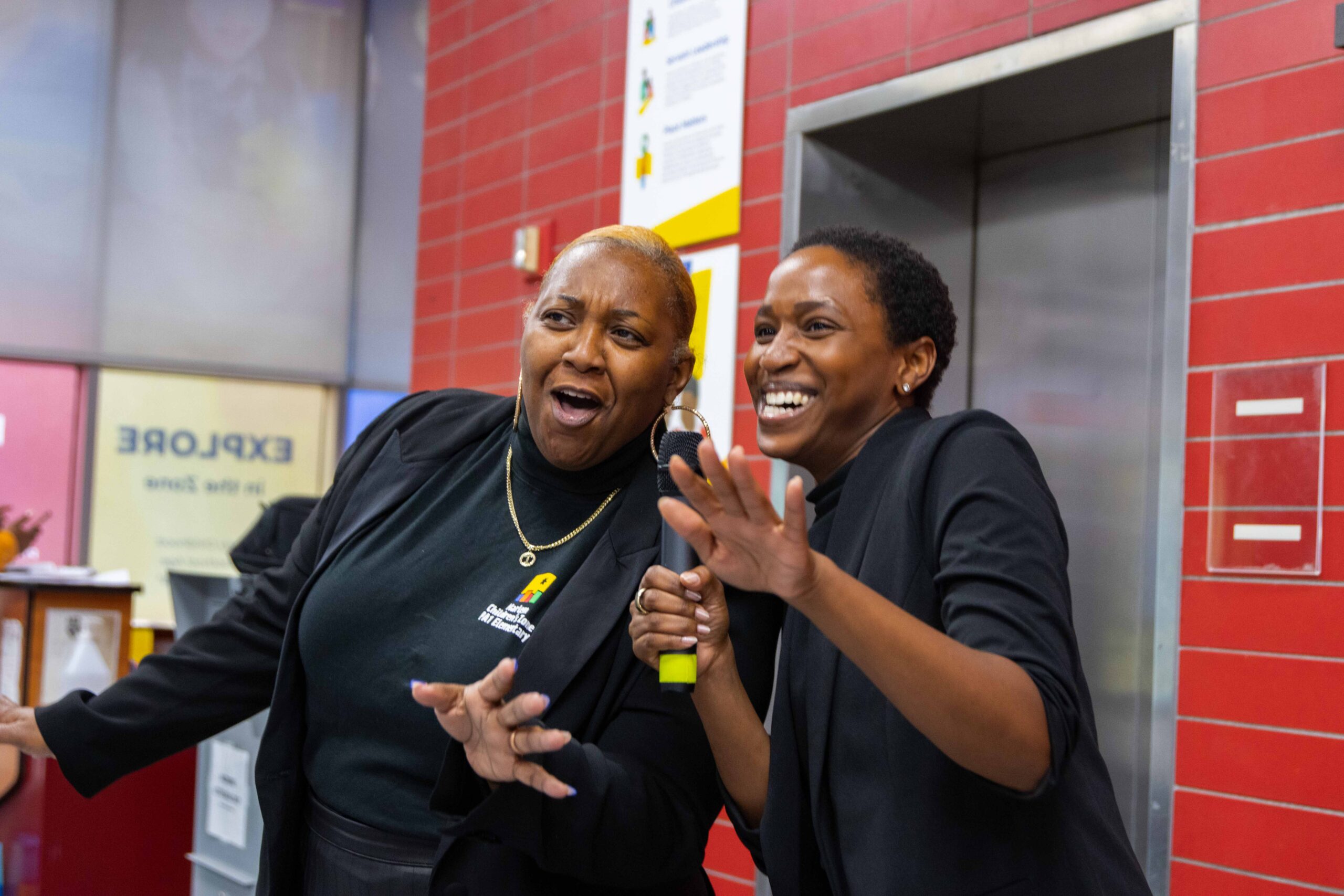 Two female staff members in the lobby singing into a microphone